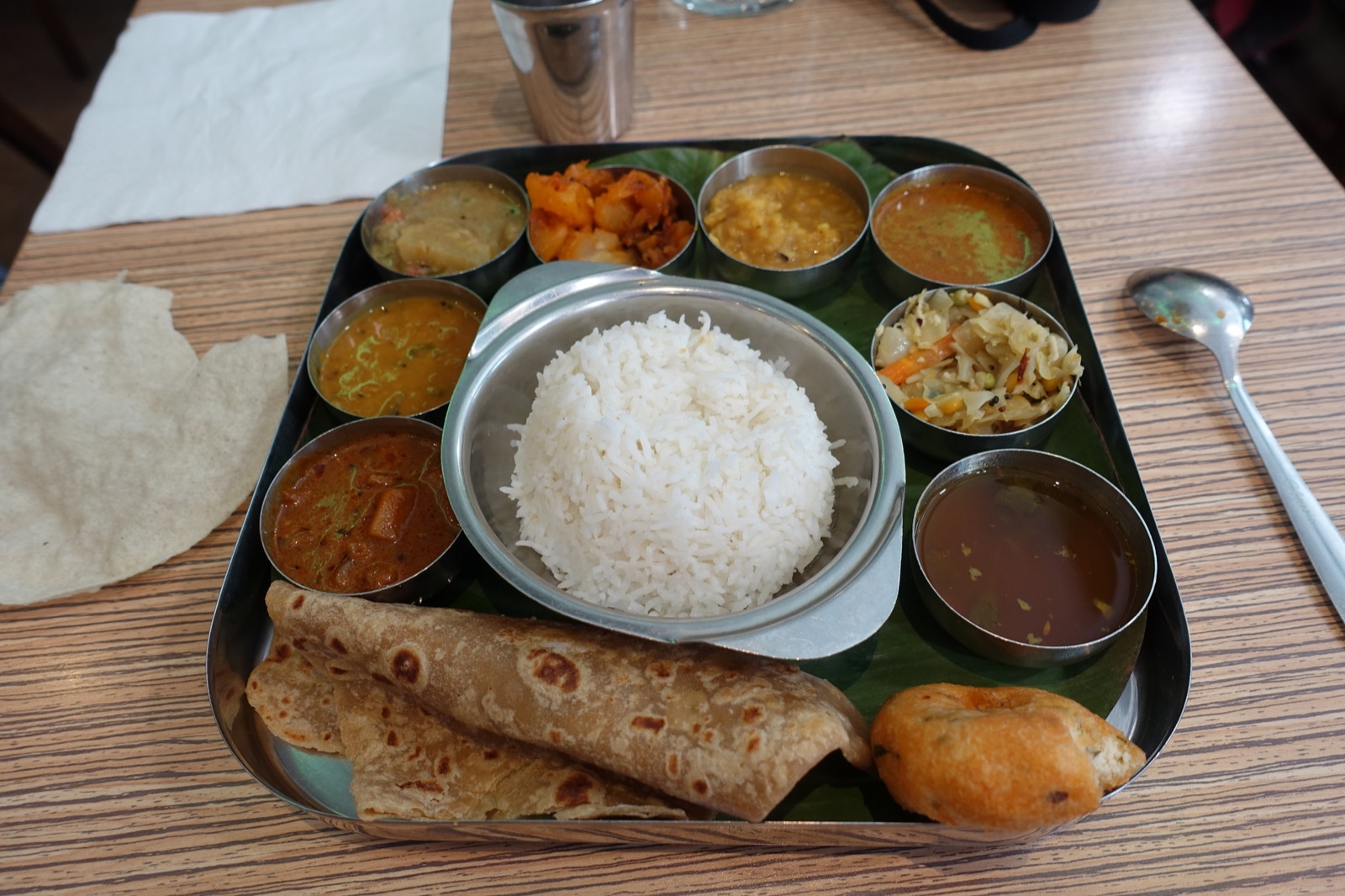 A South Indian thali with rice, curries, chapati and papad on a restaurant table
