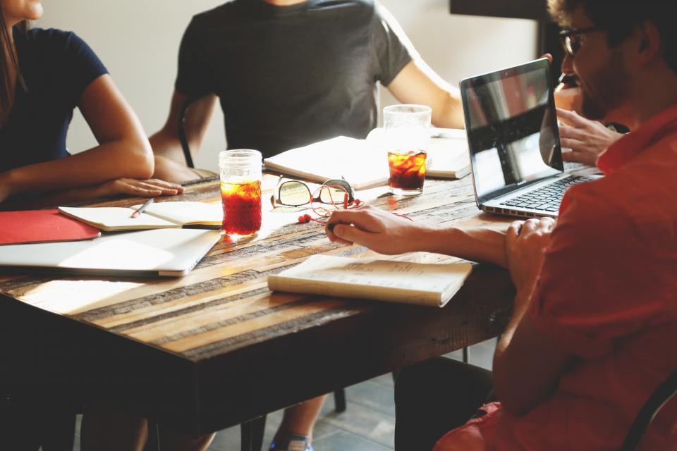 A small team around a table with laptops and notebooks, planning work